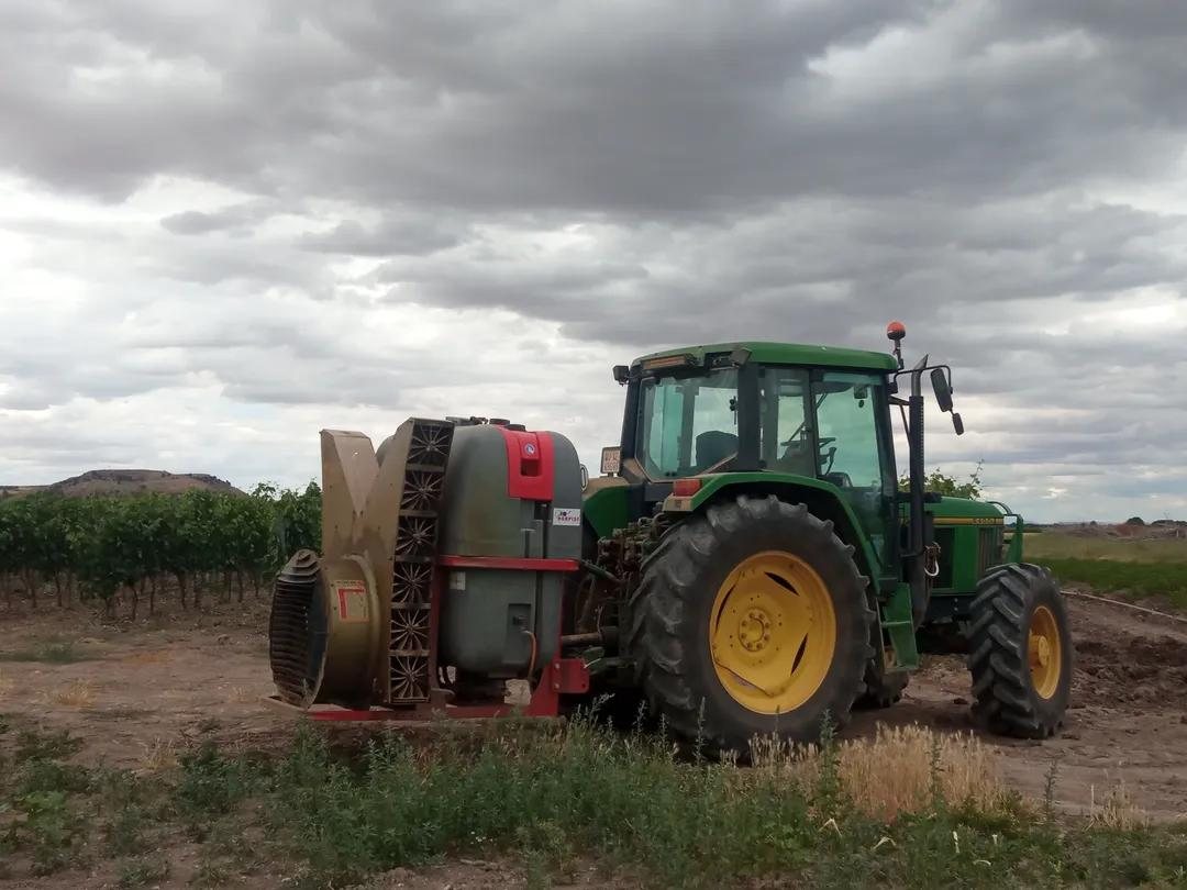 Atomizador suspendido en los tres puntos del tractor, en un viñedo
