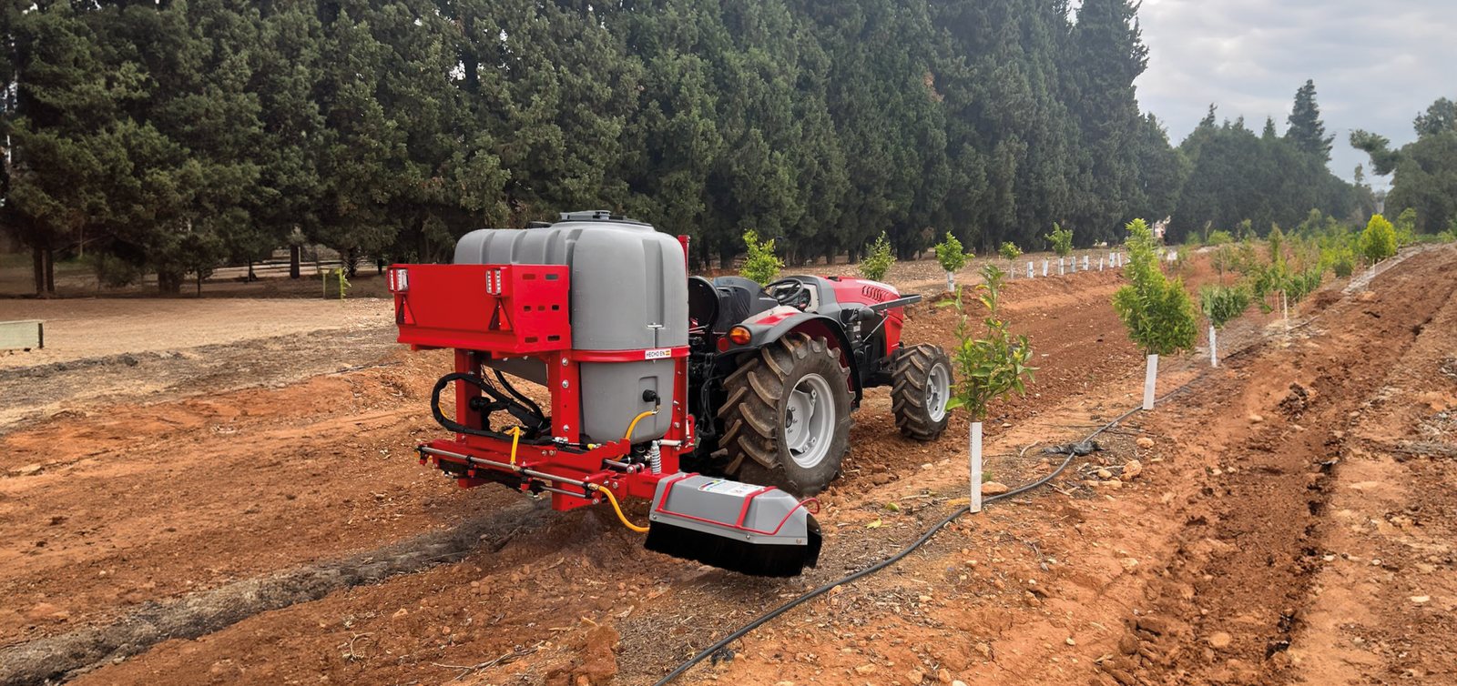 Pulverizador suspendido Delta con la barra herbicida trasera Atila-T trabajando en una plantación joven